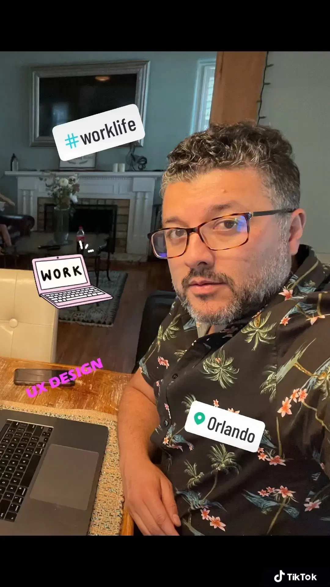 Andrei Olea seated at a table working on his laptop wearing a black shirt with palm trees